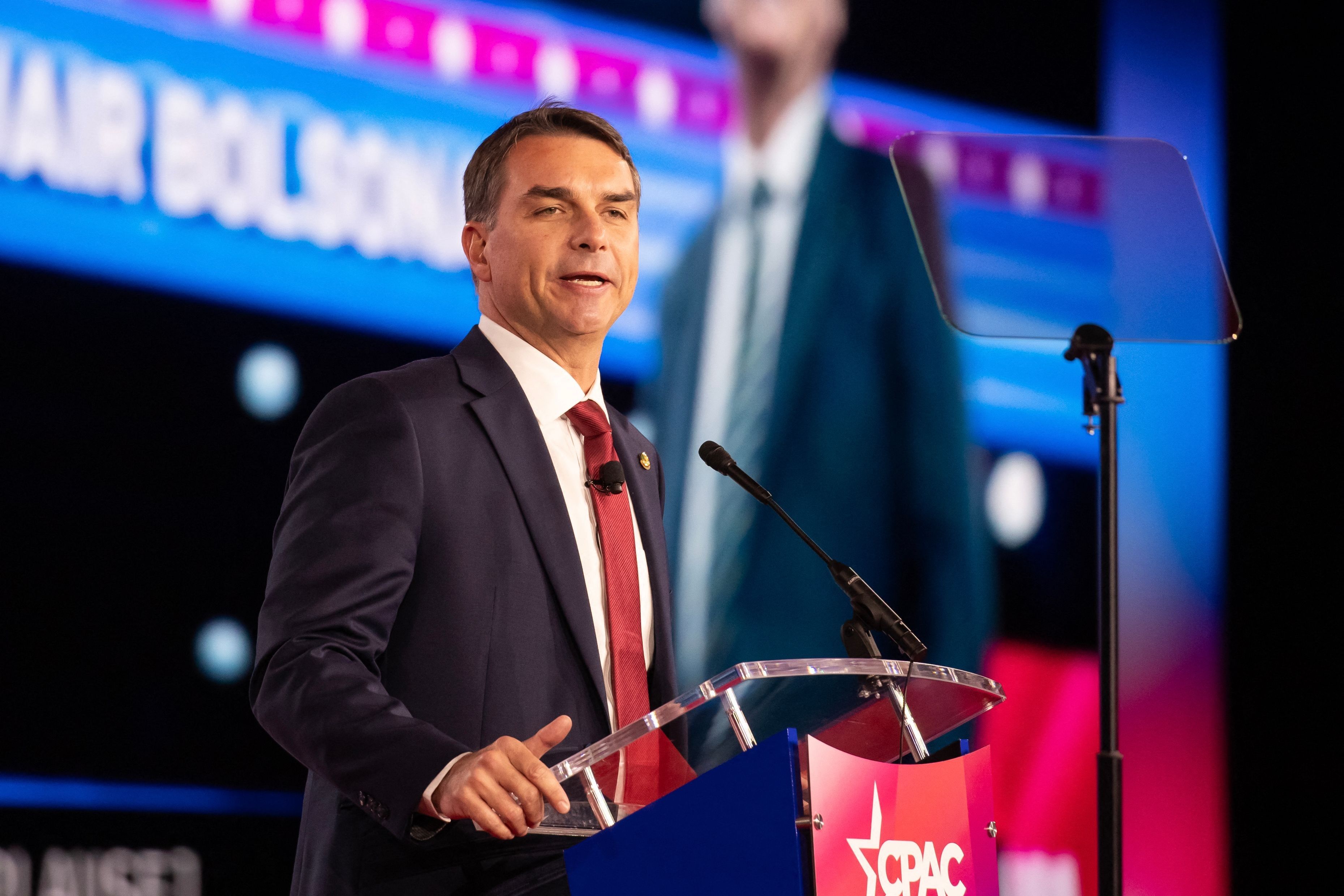 Flávio Bolsonaro fala na CPAC, enquanto aliados cobram promessas políticas. Reprodução: Oglobo