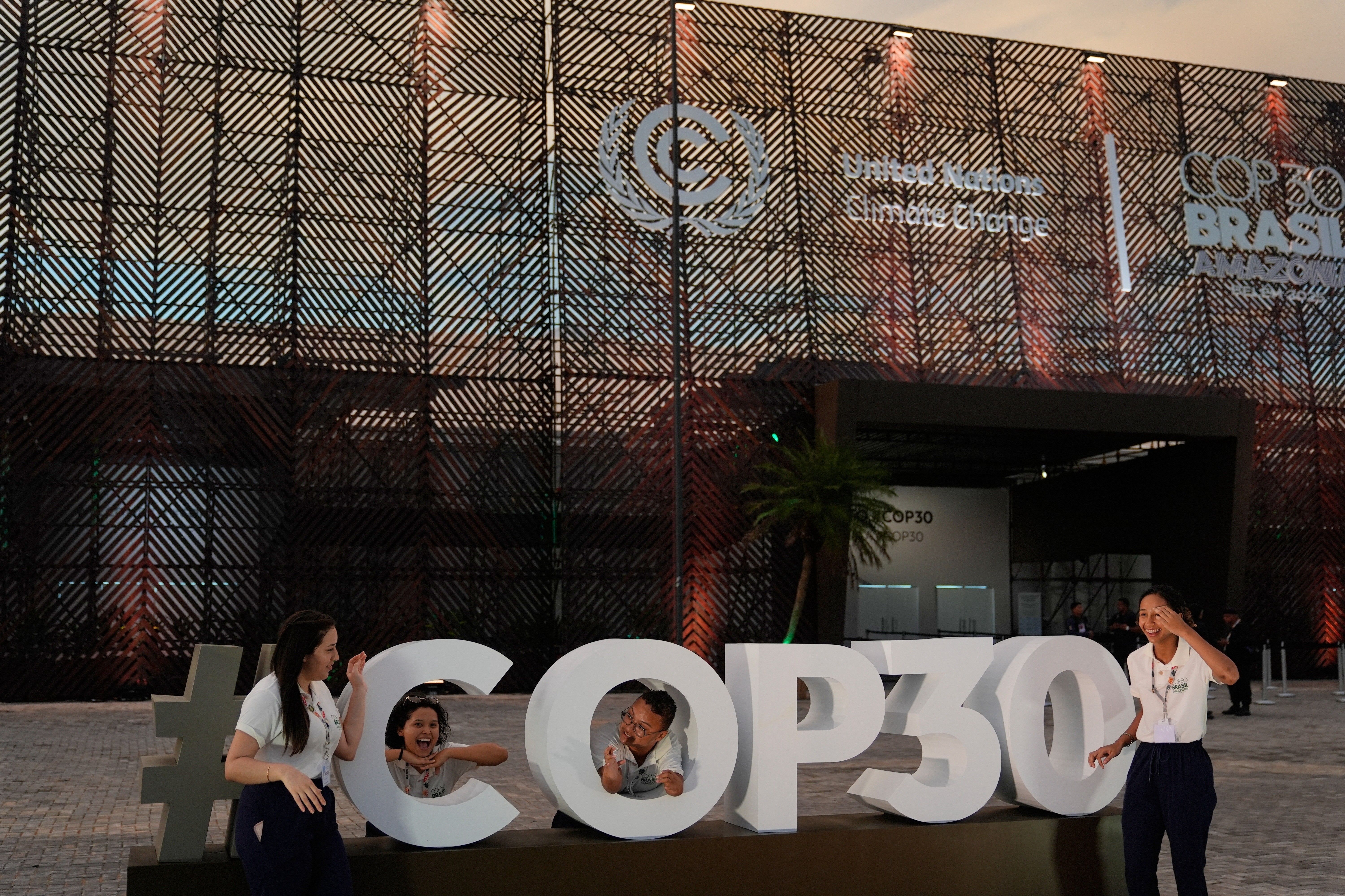 Pessoas posam diante do local da COP30 em Belém, início da conferência climática da ONU. Legenda da imagem. Reprodução: Retorno do item 11