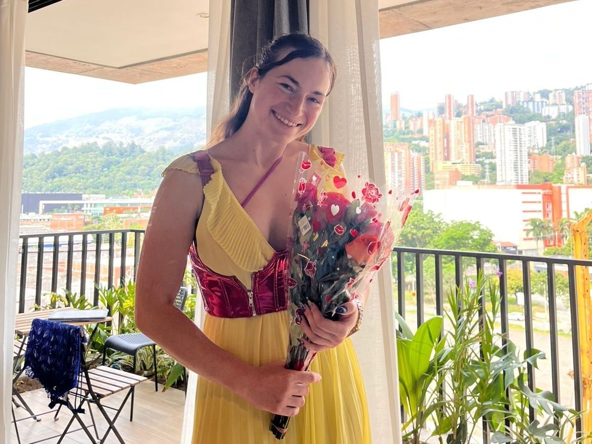 Autora celebra o primeiro dia na Colômbia, em seu novo Airbnb, segurando um buquê de flores. Reprodução: Cornelia Holzbauer