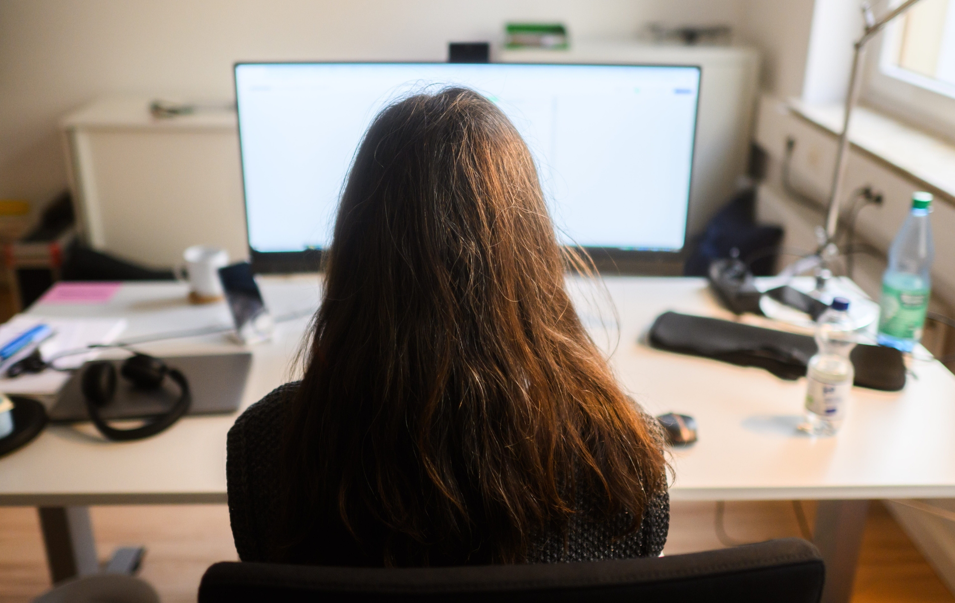 Mulher no computador simboliza o vibe coding: acelera o código, mas tem limites, dizem engenheiros. Reprodução: Business Insider