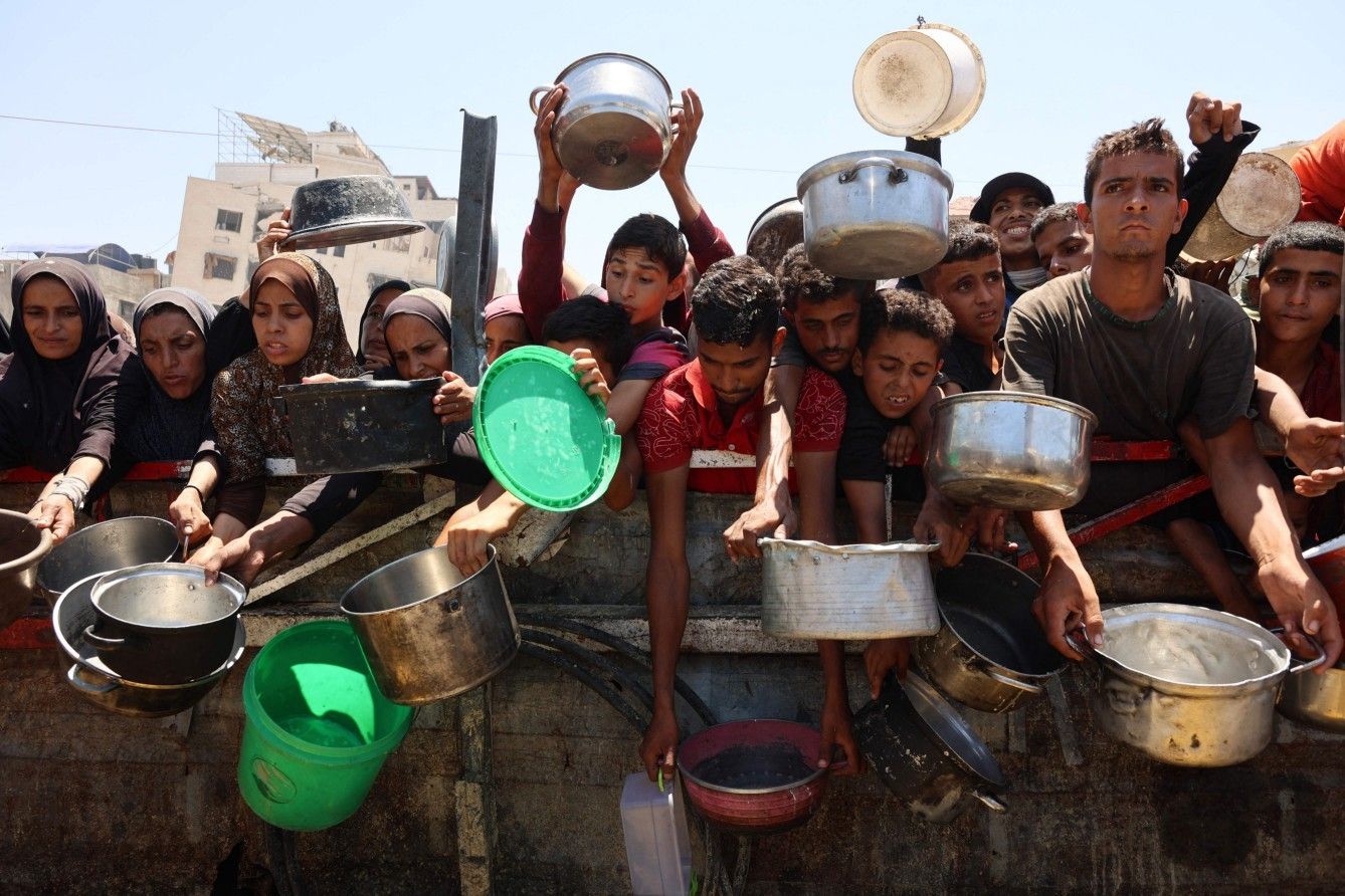 Refugiados palestinos recebem sopa em ponto de distribuição em meio à crise humanitária em Gaza.; Legenda da imagem. Reprodução: Globo