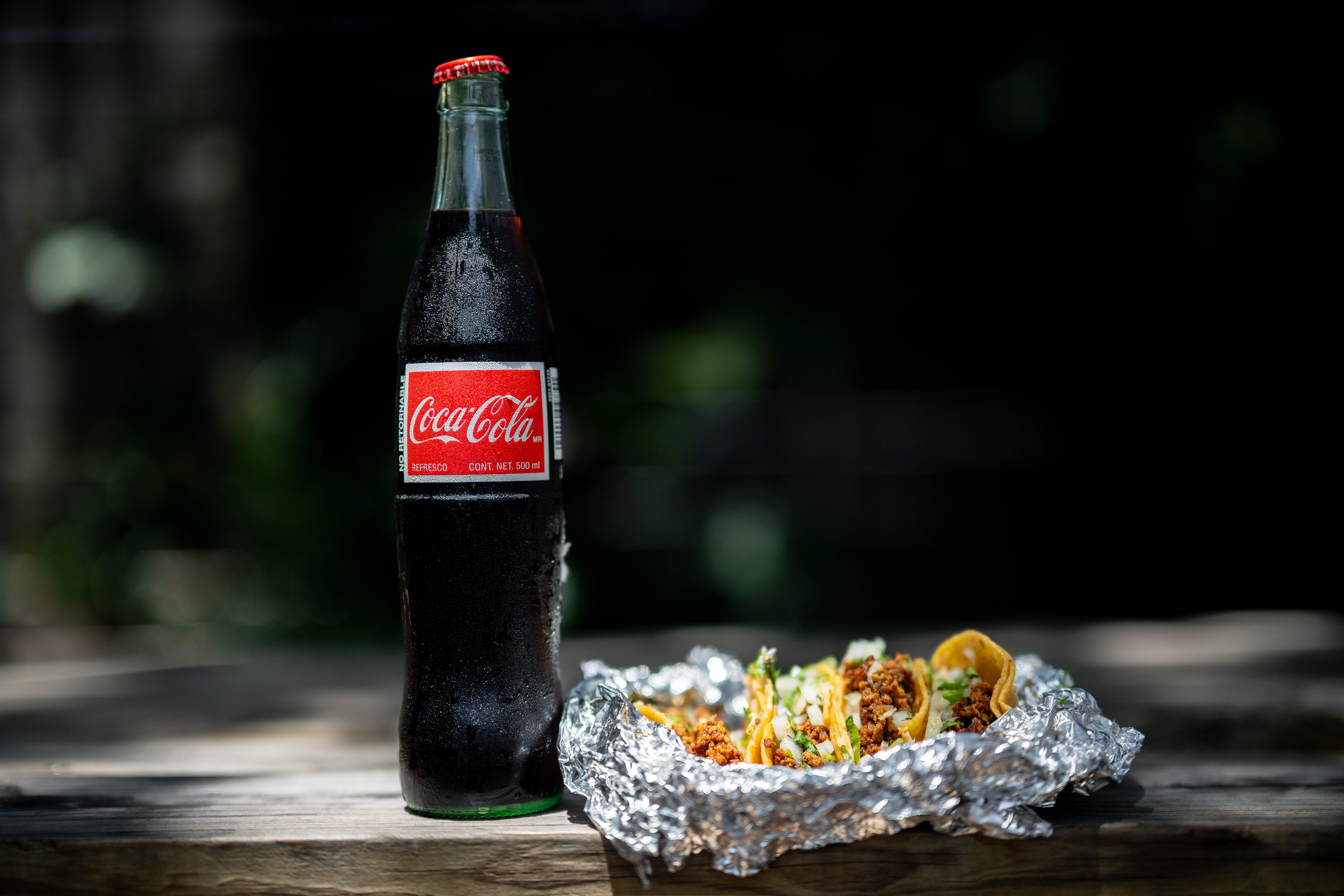 Coca-Cola importada do México ao lado de tacos, simbolizando nova versão com açúcar de cana nos EUA. Reprodução: Business Insider