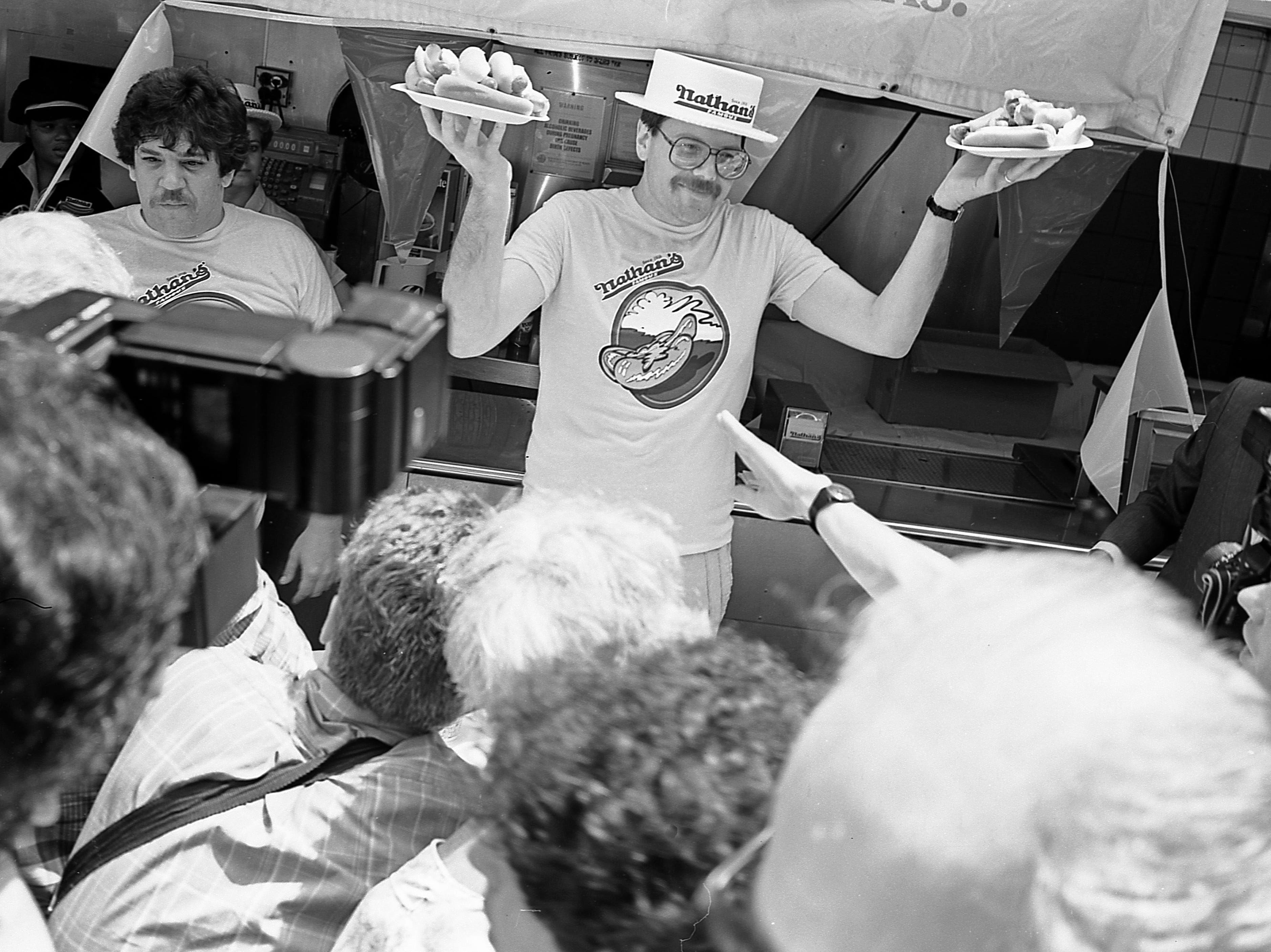 Competidores durante o concurso de comer hot dogs de Nathan's em Coney Island, em 4 de julho de 1987. Reprodução: Business Insider
