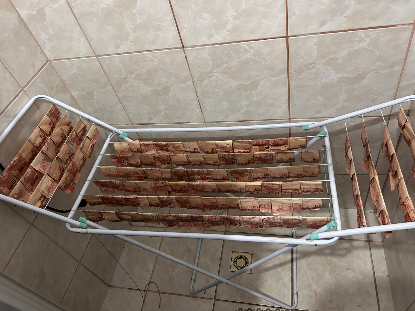 Dinheiro pendurado em varal é apreendido em operação contra lavagem de dinheiro em SC. Legenda da imagem. Reprodução: Retorno do item 11