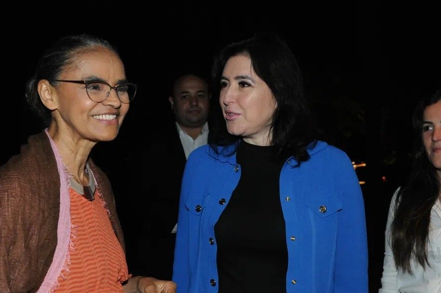 Marina Silva e Simone Tebet conversam durante evento político à noite.