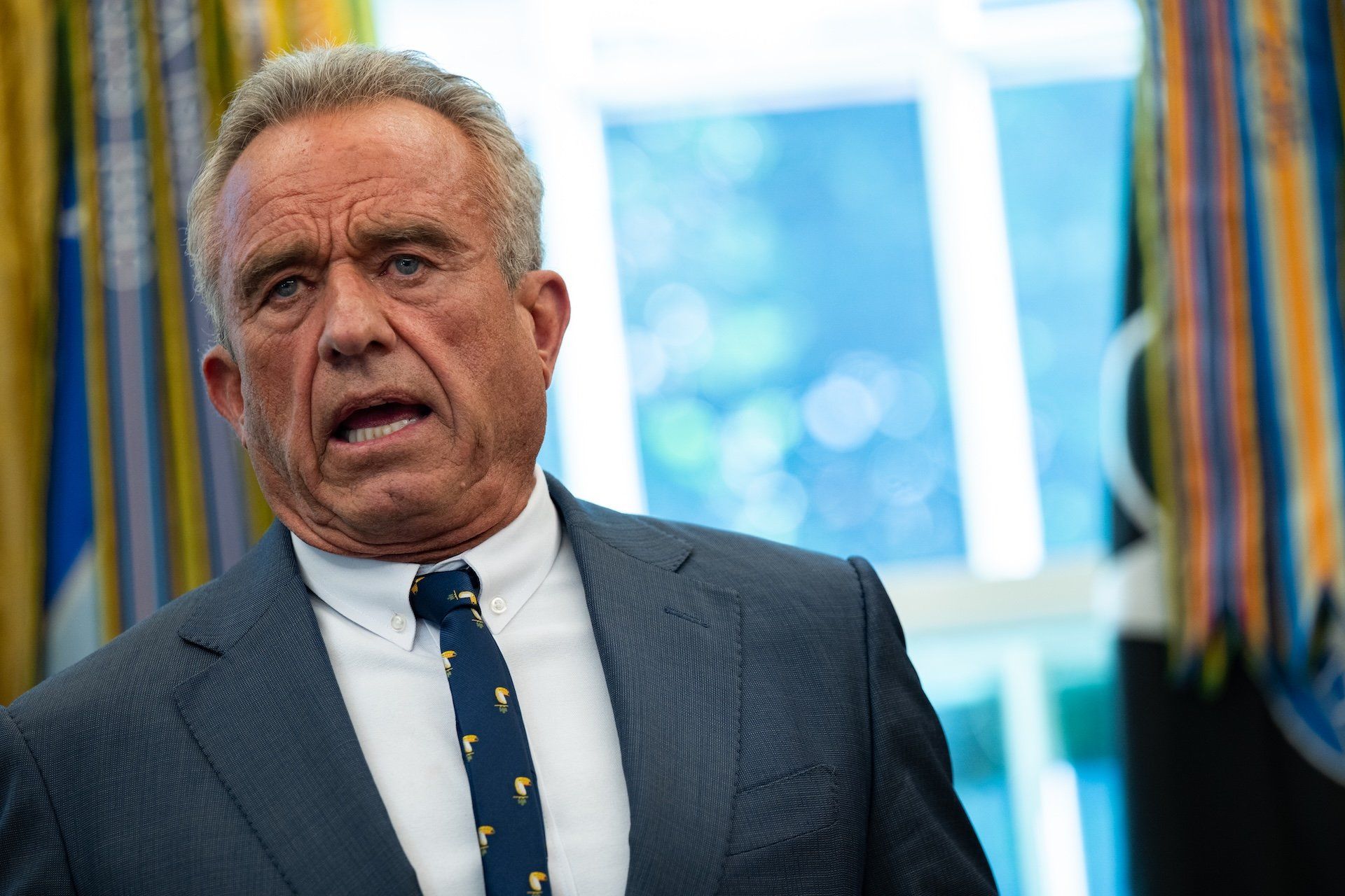 Robert F. Kennedy Jr. discute cortes em projetos de vacinas mRNA durante a assinatura de ordens executivas por Donald Trump. Reprodução: Gizmodo