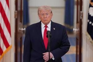 Donald Trump em cerimônia oficial na Casa Branca, com bandeiras ao fundo.