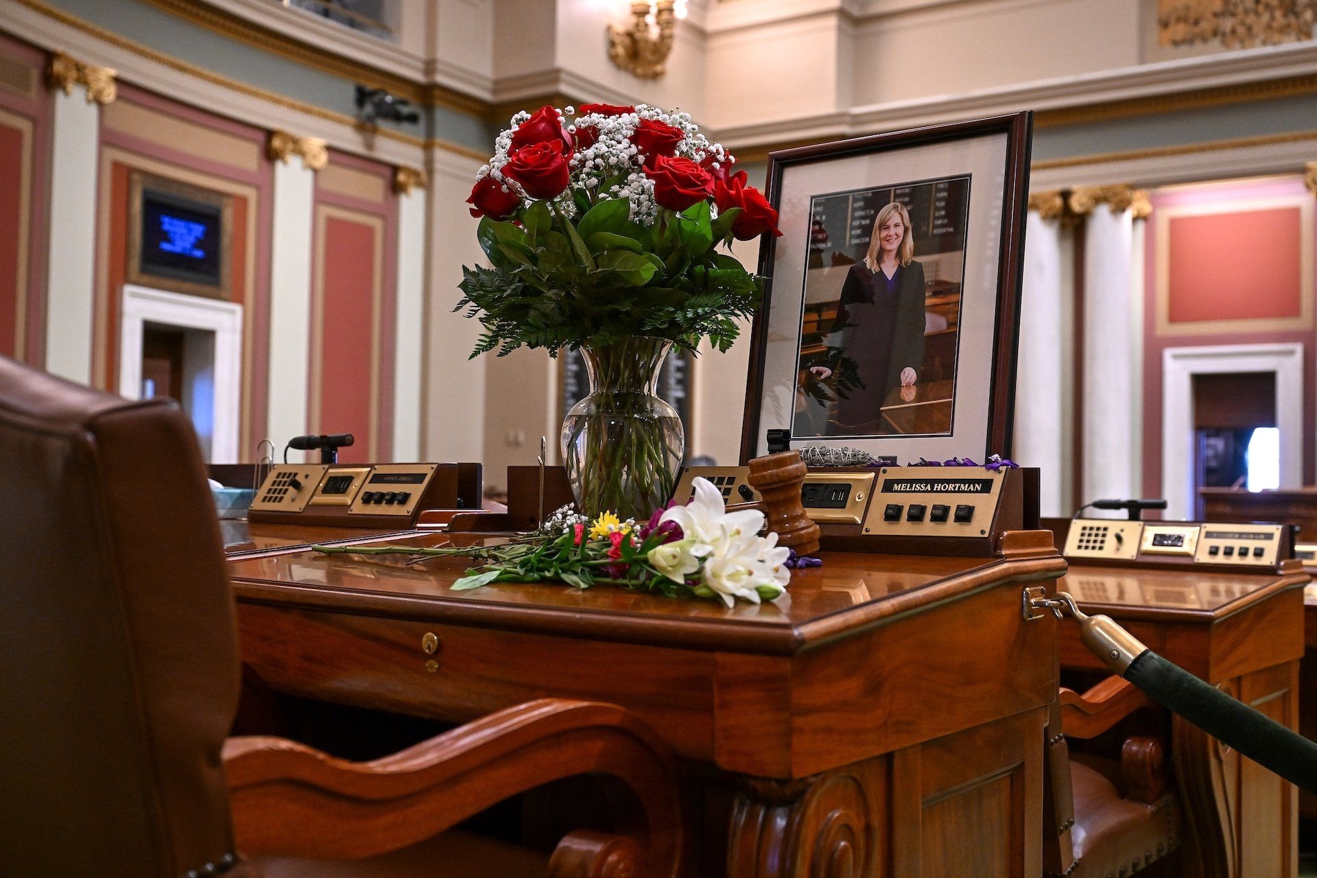 Representante Melissa Hortman na Câmara da Minnesota, rodeada por flores em seu escritório. Reprodução: Gizmodo