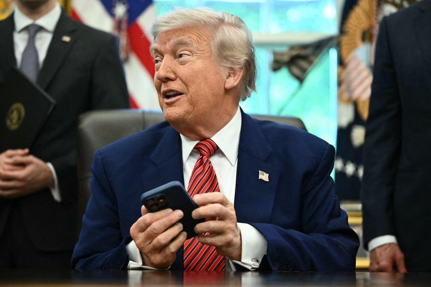 Presidente Donald Trump tenta silenciar o celular durante uma coletiva na Sala Oval. Legenda da imagem. Reprodução: Gizmodo