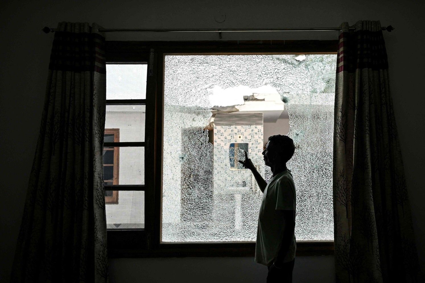 Homem mostra janela quebrada após explosões em Srinagar, violação do cessar-fogo entre Índia e Paquistão. Reprodução: Globo
