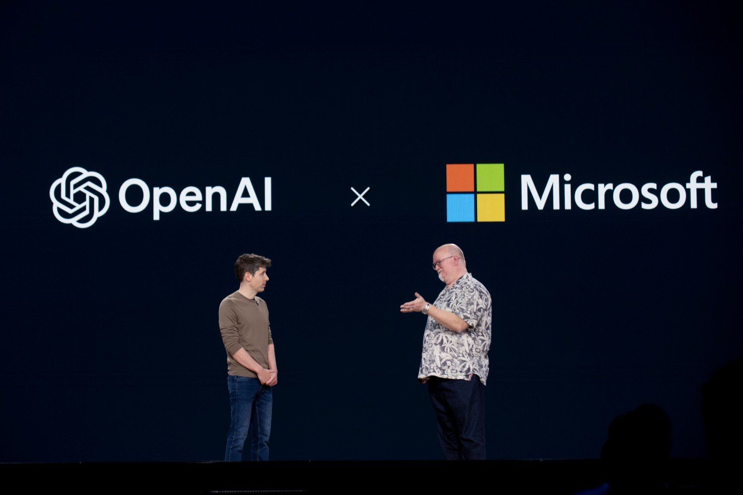 Executivos da Microsoft e OpenAI discutem investimentos em inteligência artificial no palco. Reprodução: Gizmodo