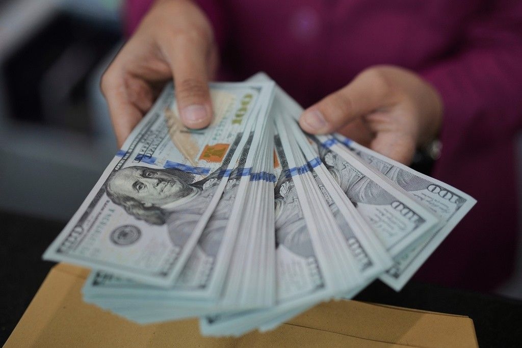 Funcionário de banco conta notas de dólar em Jacarta, enquanto o mercado financeiro reage a acordos comerciais. Reprodução: Globo