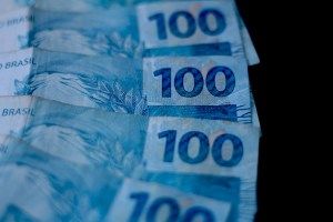 Notas de cem reais em destaque, refletindo a alta dos juros futuros após crescimento do PIB.