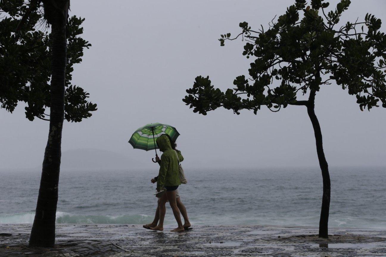[Cariocas caminham sob chuva no Rio, com previsão de granizo.]. Reprodução: Oglobo