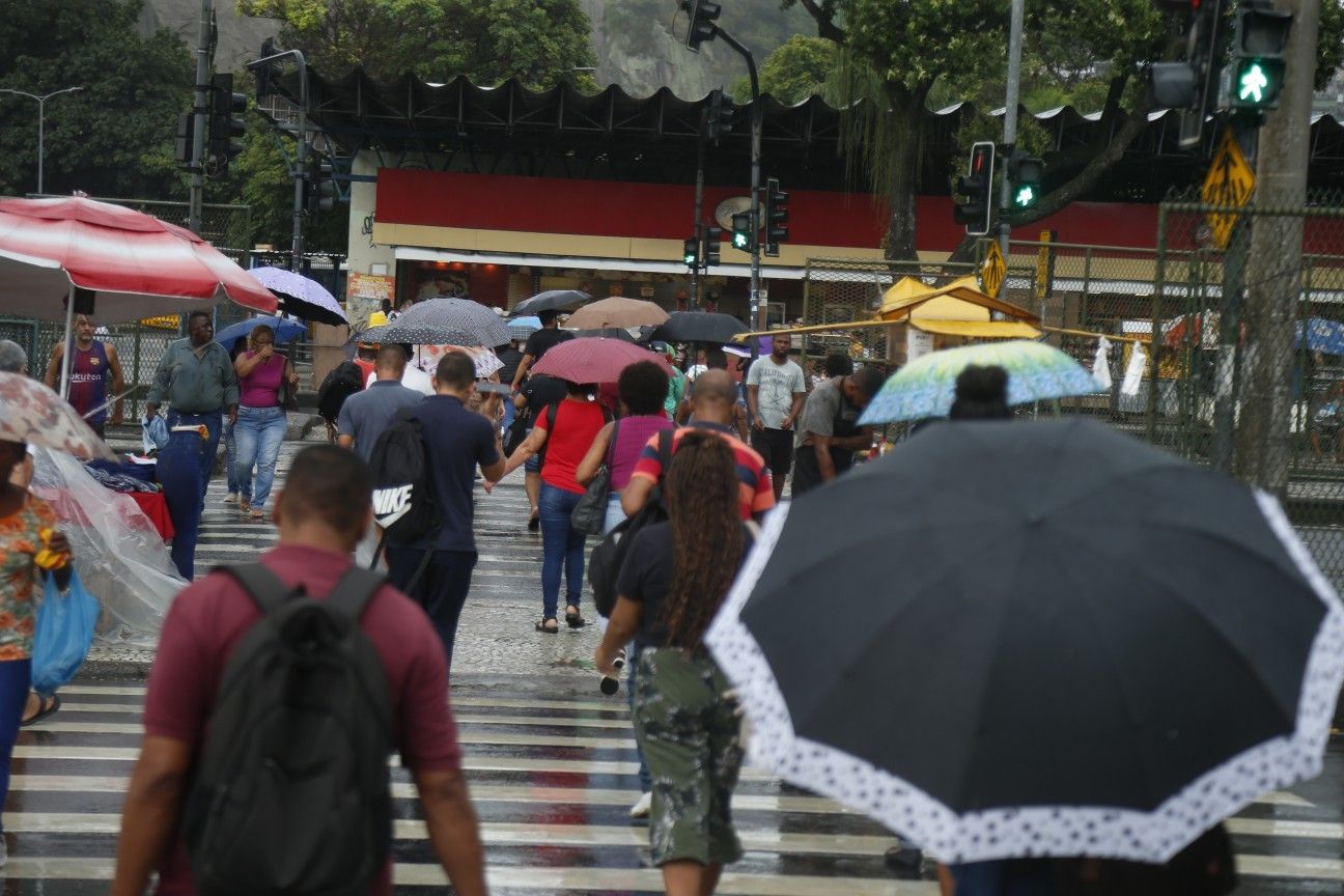 Pessoas enfrentam chuva fraca no centro do Rio de Janeiro, alertando para clima instável na região. Reprodução: Globo