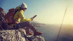 Viajante em cenário costeiro usa tablet para planejar dados internacionais com Yesim. Reprodução: Retorno do item 11