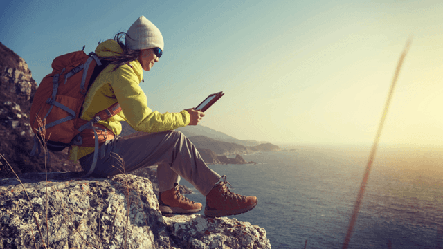 Viajante em cenário costeiro usa tablet para planejar dados internacionais com Yesim. Reprodução: Retorno do item 11