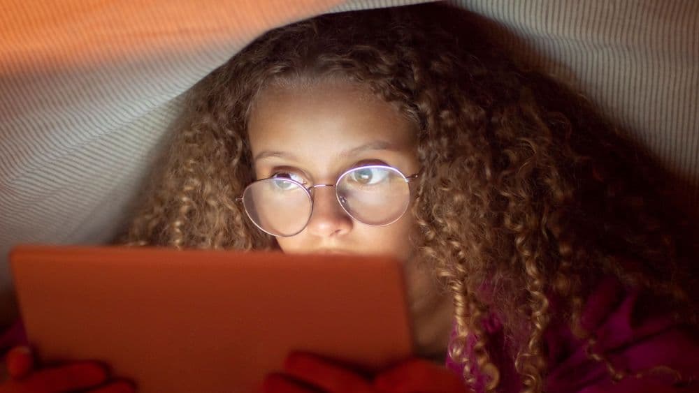 Criança usa tablet enquanto estudo revela impacto das telas no desempenho escolar na França. Reprodução: Globo