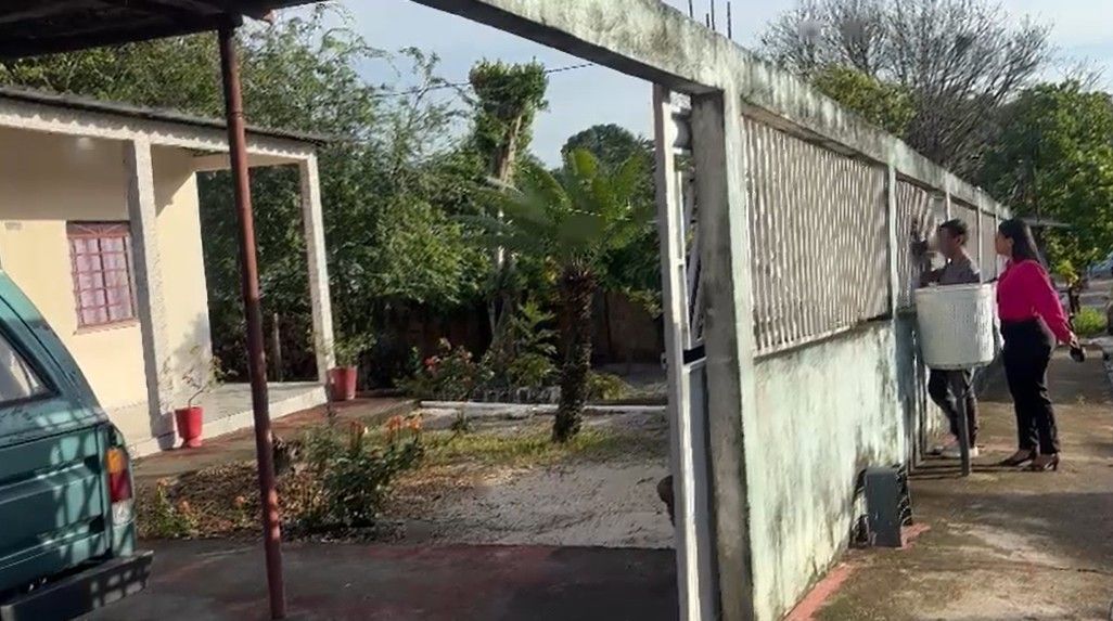 Policial e mulher conversam na entrada de casa em bairro residencial de Manaus.