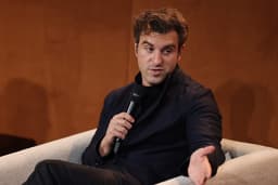 Brian Chesky ao microfone: empregos de hospitalidade devem permanecer humanos diante da IA. Legenda da imagem. Reprodução: Retorno do item 11