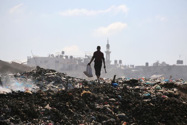 Homem busca itens em lixão em Rafah, onde Israel planeja criar área humanitária para deslocamento de palestinos.; Legenda da imagem. Reprodução: Globo