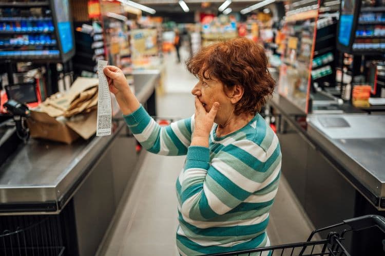 Mulher idosa examina um recibo em supermercado, alerta sobre bisfenóis perigosos. Legenda da imagem. Reprodução: Business Insider