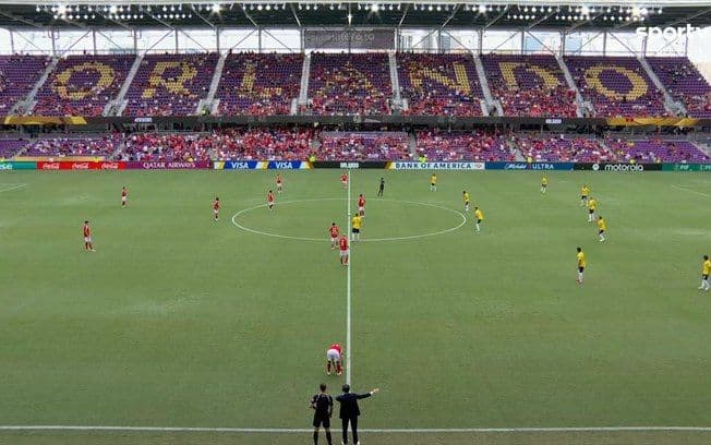 Público se abriga no Orlando City Stadium durante partida entre Benfica e Auckland; Legenda da imagem. Reprodução: Esporte IG