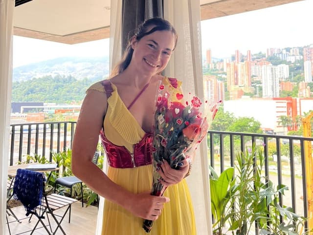 Autora celebra o primeiro dia na Colômbia, em seu novo Airbnb, segurando um buquê de flores. Reprodução: Cornelia Holzbauer