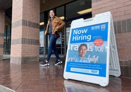 Cliente passa por placa de 'contratando' em frente a loja Ross, após demissão de chefe do BLS por Trump. Reprodução: Justin Sullivan/Getty Images