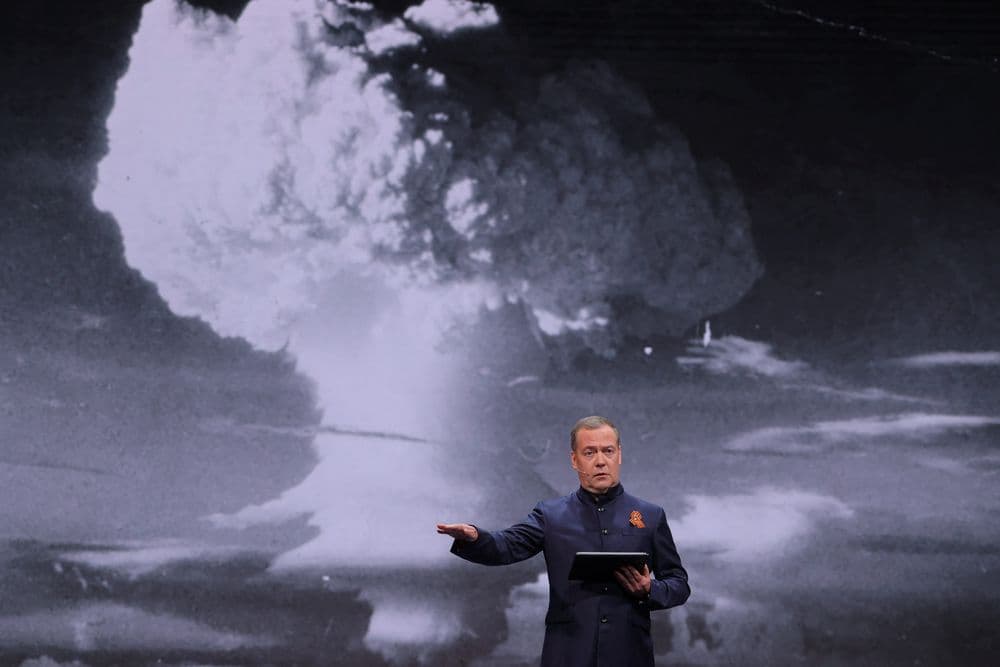 Dmitry Medvedev discursa durante maratona educacional em Moscou, enquanto imagem de nuvem de cogumelo aparece ao fundo. Reprodução: Business Insider