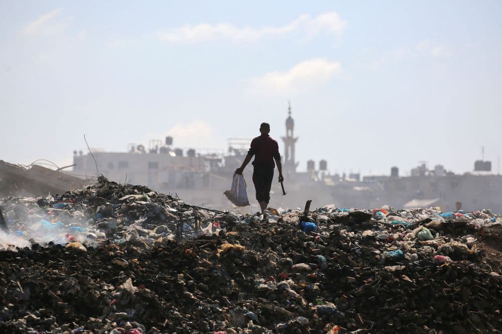 Homem busca itens em lixão em Rafah, onde Israel planeja criar área humanitária para deslocamento de palestinos.; Legenda da imagem. Reprodução: Globo