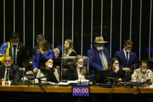 O deputado usa esparadrapo na boca durante protesto na Câmara contra prisão domiciliar de Jair Bolsonaro. Legenda da imagem. Reprodução: Globo
