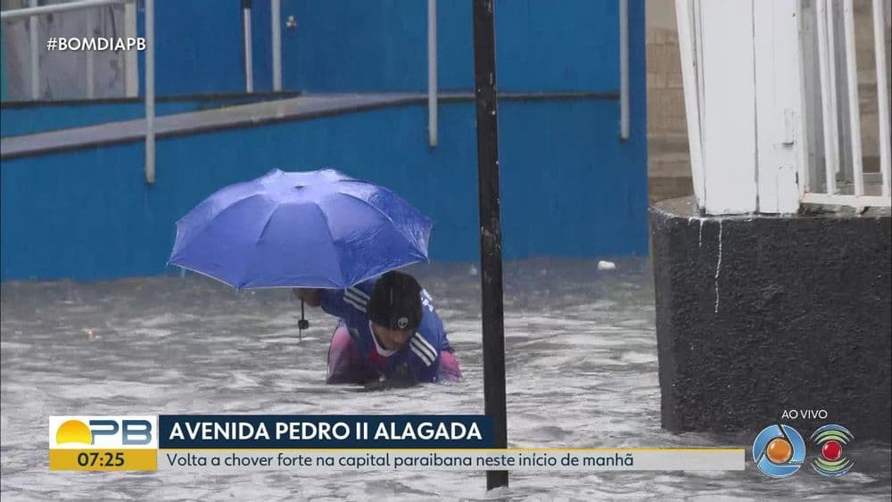Morador tenta desobstruir bueiro em rua alagada de João Pessoa durante forte chuva. Reprodução: Globo