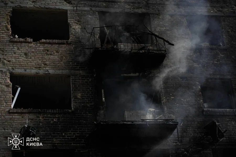 Edifício danificado por ataque aéreo em Kiev, com fumaça e janelas quebradas.