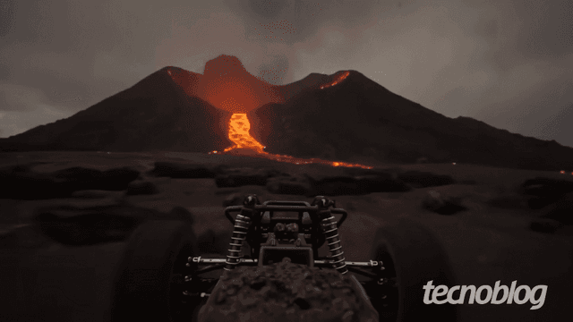 Carro de controle remoto navega em cenário gerado pelo Genie 3, com vulcão em erupção ao fundo. Reprodução: Tecnoblog