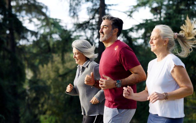 Grupo de adultos praticando corrida ao ar livre em ambiente natural.