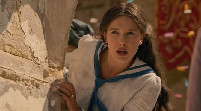 Millie Bobby Brown em cena de 'Enola Holmes 3', com expressão de surpresa.
