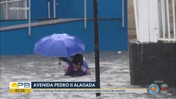 Morador tenta desobstruir bueiro em rua alagada de João Pessoa durante forte chuva. Reprodução: Globo