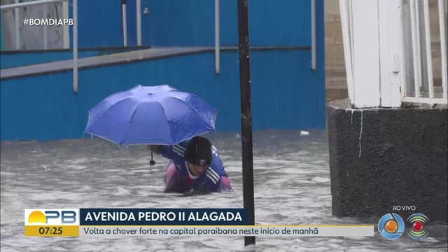 Morador tenta desobstruir bueiro em rua alagada de João Pessoa durante forte chuva. Reprodução: Globo