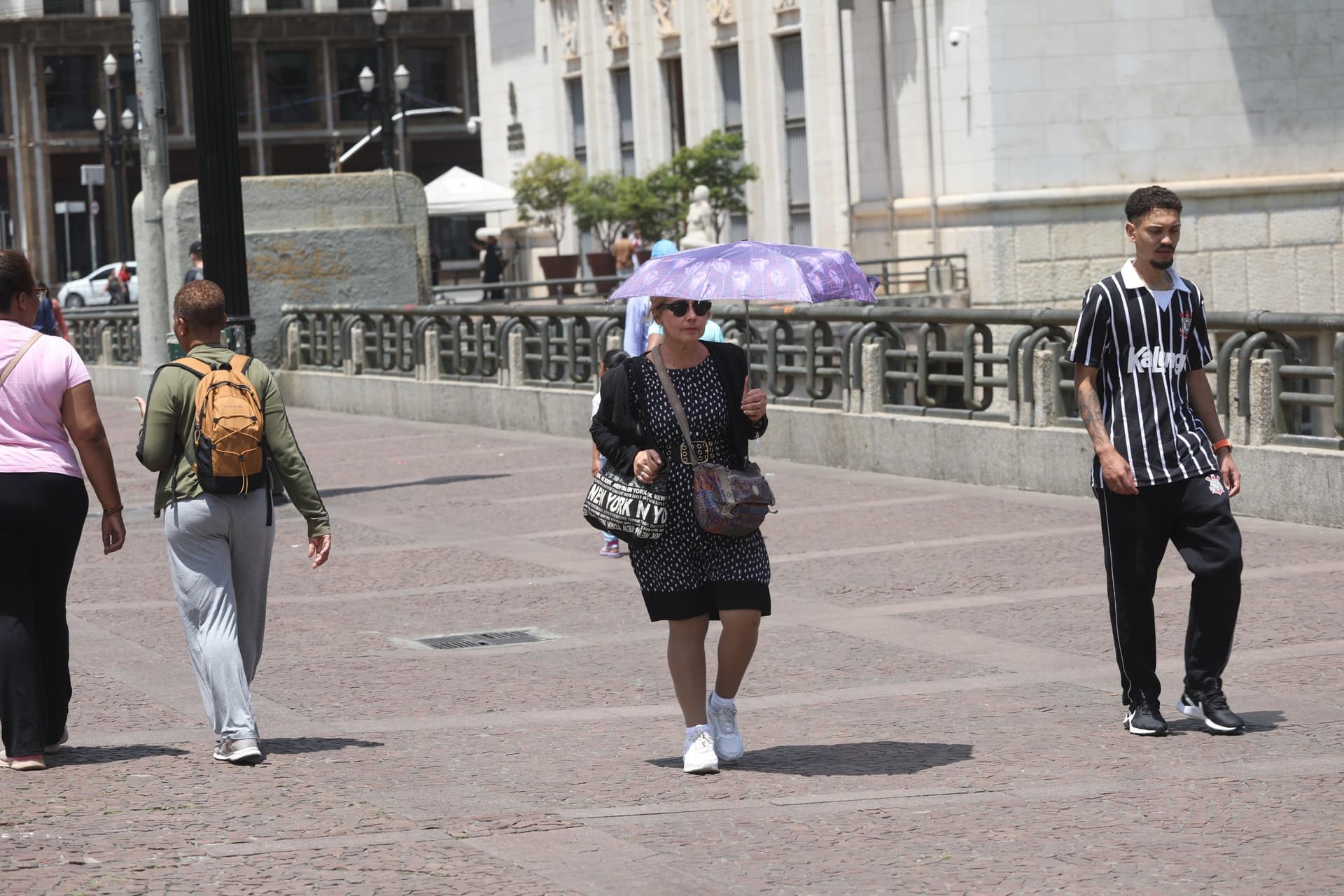 Pedestres enfrentam calor intenso no centro de SP, com frente fria prevista e queda de temperatura. Reprodução: G1