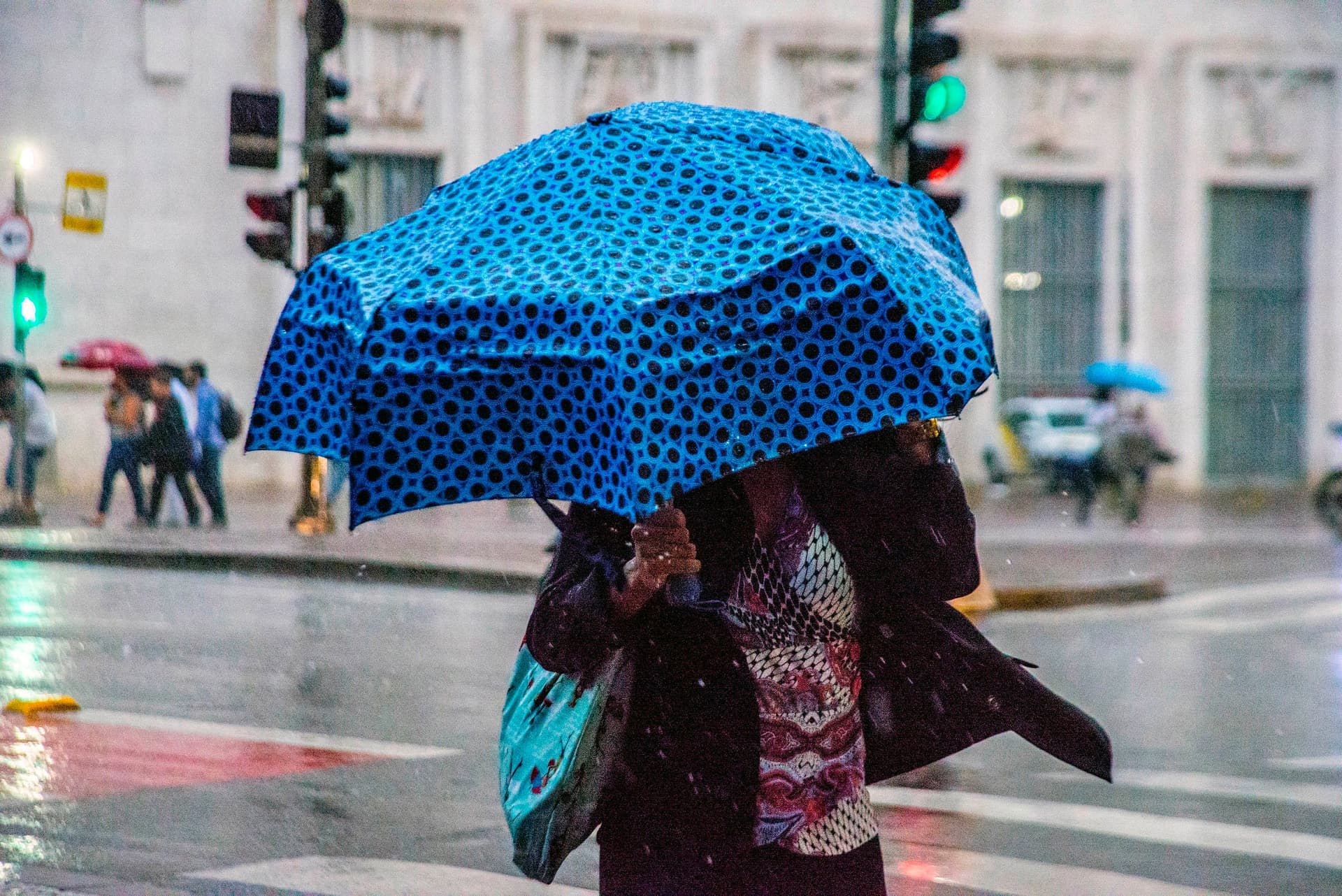 Pedestres se protegem da chuva na região central de São Paulo com a frente fria se aproximando. Reprodução: Globo