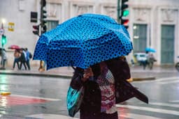 Pedestres se protegem da chuva na região central de São Paulo com a frente fria se aproximando. Reprodução: Globo