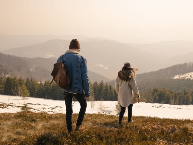 Casal caminha em direção às montanhas, refletindo sobre como a mudança para uma cidade pequena fortaleceu seu casamento. Reprodução: Serhii Mazur/Getty Images