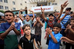 Crianças palestinas comemoram em frente a hospital na Faixa de Gaza. Legenda da imagem. Reprodução: Retorno do item 11