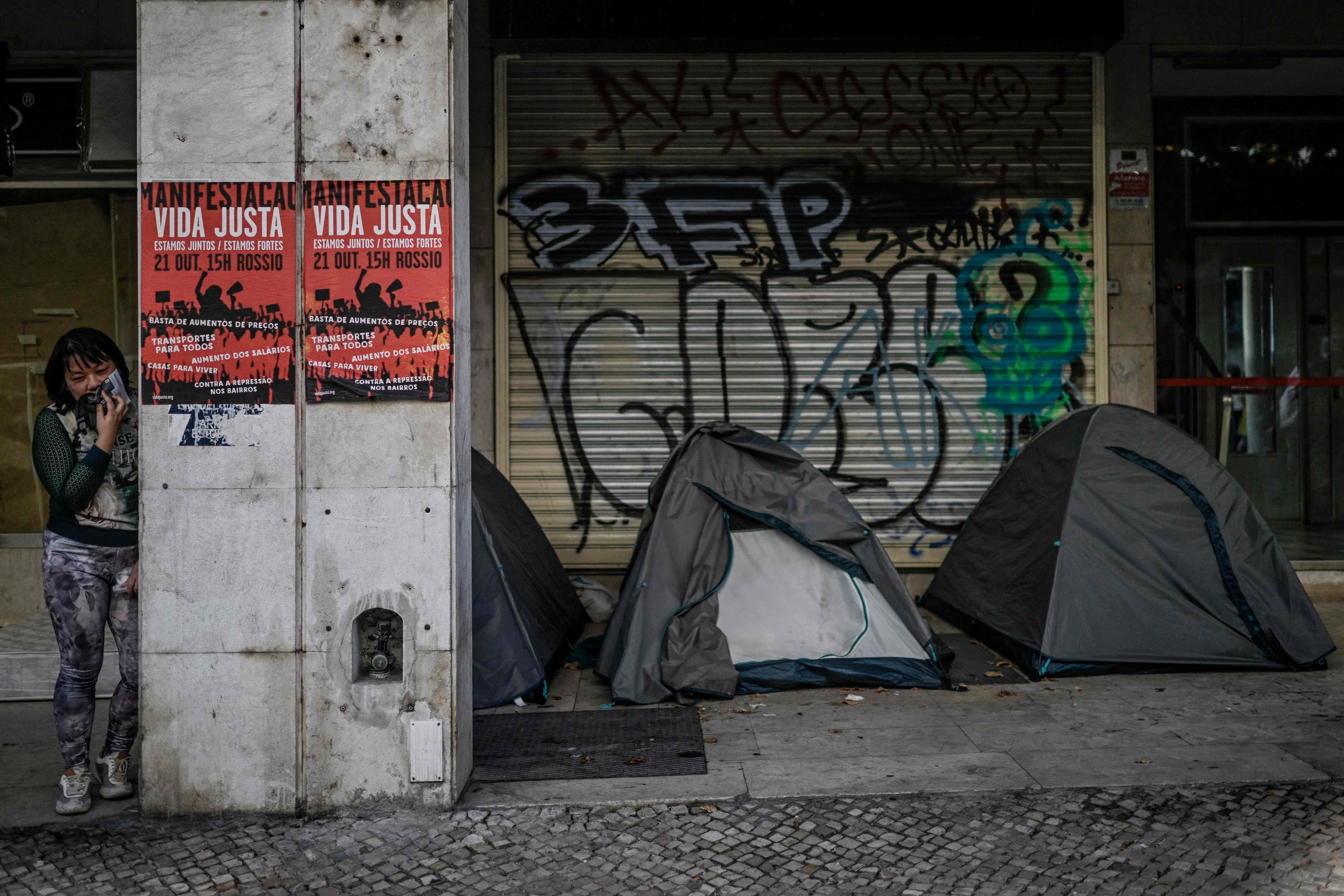 [Mulher perto de tendas em Lisboa durante protesto por moradia]. Reprodução: Oglobo