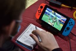 Competidor faz anotações enquanto joga Pokémon no Nintendo Switch durante o Campeonato Mundial de Pokémon em Londres. Reprodução: John Keeble/Getty Images