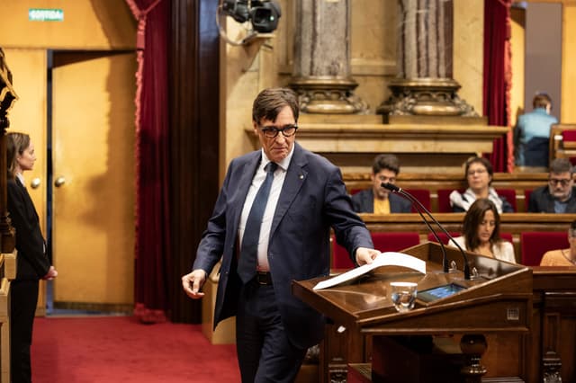 Legenda da imagem. Salvador Illa no estrado durante o debate sobre habitação no Parlamento, apresentando planos para construção de moradias. Reprodução: Retorno do item 11
