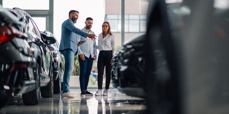 Casal conversa com vendedor em concessionária, considerando a compra de um carro novo. Reprodução: Business Insider
