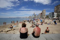 Turistas desfrutam da praia em Benidorm, enquanto se prepara a nova edição de viagens para idosos. Legenda da imagem. Reprodução: El País