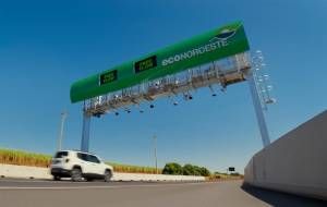 Veículo passa por sistema de pedágio free flow sem praças físicas visível na rodovia.